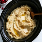 slow cooker mashed potatoes ready to serve with wooden spoon.